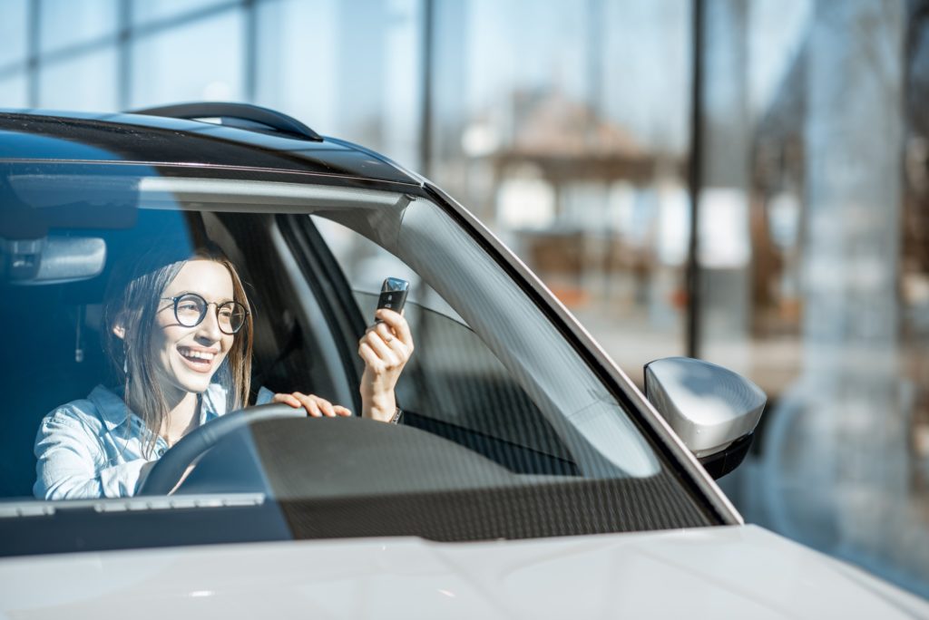 Happy woman with keys in the car